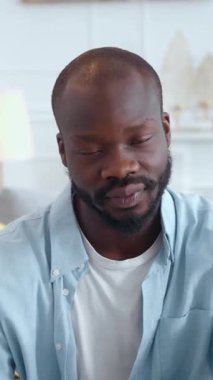 Düşünceli bir adam sessizce oturur, modern, parlak ve davetkar bir ortamda çeşitli fikirleri derinden yansıtır.