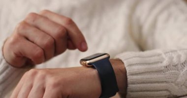 Akıllı, genç ve modern bir adamın elleri. Beyaz kazaklı adam elektronik saate dokunuyor. Kapalı.