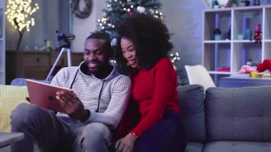 NEW YORK - 13 Aralık, 2017. Genç ve çekici Afrikalı çift pembe dijital tablette film izliyor. Elektronik aletleri elinde tutan adam. Kıvırcık kız saç düzeltiyor. Çıkmak. Kutlama atmosferi.