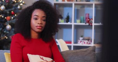 Güzel Afrikalı kız televizyon kanallarını değiştiriyor. Genç bir kadın TV ekranında korkunç bir şey izliyor. Güzel bir odada yastığın arkasına saklanan korkmuş kız..