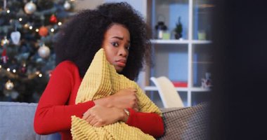 Gece yarısı yalnız başına korku filmi izleyen genç Afrikalı bir kadın. Oturma odasındaki kanepede oturan ve sarı yastığın arkasına saklanan bir kız. Kapalı alanda. Kutlama atmosferi.