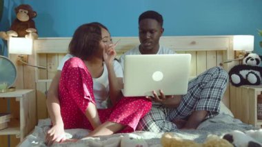 Genç, hoş, Afrikalı tatlı bir çift. İnternette internette geziniyorlar. Yatakta uzanıp sohbet ediyorlar..