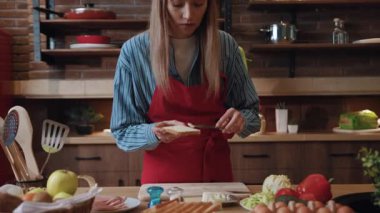 Akşam yemeği için sandviç ve salata pişiren güzel bir genç bayanın portresi. Güzel bir çift evdeki mutfakta öpüşüyor ve yemek pişiriyor..