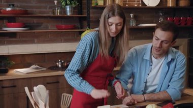 Birbirlerine aşık güzel genç bir çift mutfakta yemek pişiriyor ve yemek yiyorlar. Gülümseyen bir kadının portresi sandviç pişiriyor ve evde kocasını besliyor..