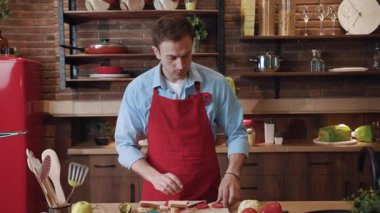 Yetenekli, çekici genç aşçının portresi. Sandviç yapıyor. Evde şık bir mutfakta lezzetli bir öğle yemeği pişiriyor..