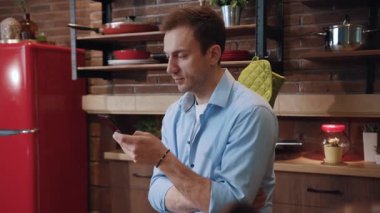 Mutfak masasına dayanan bir akıllı telefondan ciddi şekilde konsantre olmuş bir adam haberlere göz atıyor. Başarılı iş adamlarının profili cep telefonundan haberleri okuyor ve evde dinleniyor.