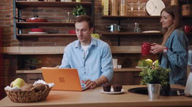 Karısıyla birlikte dizüstü bilgisayarla mutfakta kahvaltı hazırlamakla meşgul genç adam. Sevgi dolu bir çiftin portresi kahve içiyor ve güzel bir sabahı birlikte geçiriyorlar..