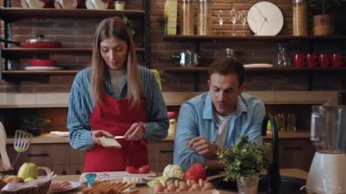 Yakışıklı, neşeli karı koca yemek pişiriyor ve mutfakta birlikte sohbet ediyorlar. Güzel bir çift evde yemek yaparak güzel bir akşam geçiriyor..