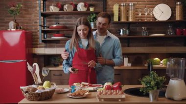 Mutfaktaki neşeli, genç bir ailenin portresi. Sevgi dolu koca, karısını kucaklıyor modern mutfakta iki kişilik lezzetli bir yemek pişiriyor..