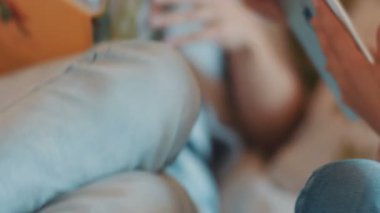 Yatakta yatan yeni gümüş dijital tablet. İki kız elinde tabletle geziyor. Mutlu anne ve kız ekrana bakıp gülümsüyor. Yakın plan..