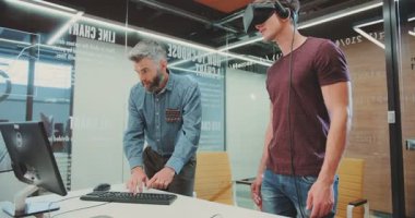 NEW YORK - 5 Nisan 2017: Sanal gerçeklik gözlüklerini test eden iki çekici erkek. Bilgisayar klavyesinde yazan adam. Araştırma Merkezi. Genç adam etrafa bakıyor, yeni icatlar kullanıyor..