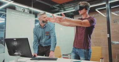 NEW YORK - 5 Nisan 2017: Genç yakışıklı programcı sanal gerçeklik gözlükleriyle uzaya bakıyor. Modern donanımlı ofiste çalışan yakışıklı, güler yüzlü adam..