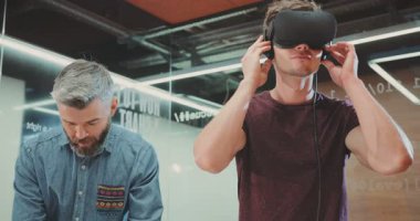 NEW YORK - 5 Nisan 2017: Sanal gerçeklik gözlüklü genç çekici adam farklı yönlere bakıyor. Ofiste yeni icatlar kullanan çekici ve zeki programcılar. Kapalı.