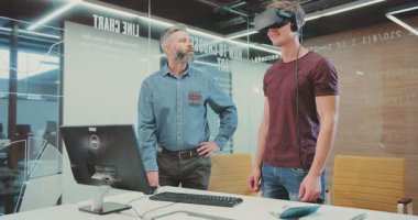 NEW YORK - 5 Nisan 2017: Teknik Üniversitesi Bilim Merkezi 'nde sanal gerçeklik gözlüklerini test eden iki çekici adam. Hoş bir adam, sıradan kıyafetler içinde. Ellerine bakıyor, gülümsüyor..