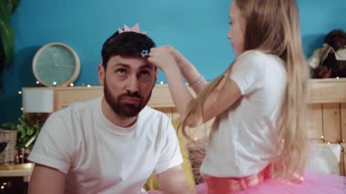 Yakışıklı sakallı bir babanın portresi kızına bakarken kafasına saç tokası takıyor. Babası ve küçük kızı doğum günü partisi için hazırlanıyorlar..