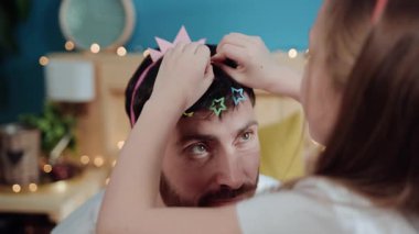 Kızıyla oynarken babasının yardım için ağlamasının portresi. Saçında saç tokaları olan, prenses gibi giyinmiş, çocuğuyla yatakta oturan zavallı yorgun bir baba..