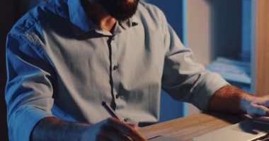 Adanmış bir birey, ahşap bir masada geç saatlere kadar çalışırken detaylı notlar yazarak bağlılığını gösteriyor.