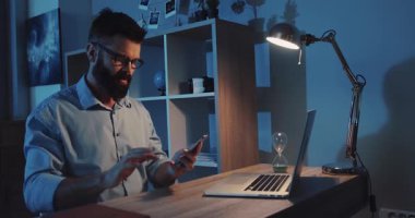 Bir dizüstü bilgisayar ve lambayla uzun saatler çalışan kendini adamış ve üretkenlik gösteren kendini adamış bir profesyonel.