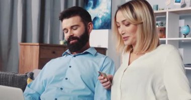 Genç bir çift, rahat ve modern bir yaşam alanında fikirlerini paylaşan bir dizüstü bilgisayarla derinden meşgul.