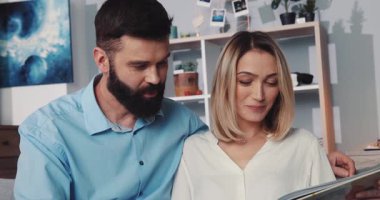 Sevgi dolu bir çift, şık oturma odalarında birlikte çok sevilen bir fotoğraf albümüne bakmaktan zevk alır.