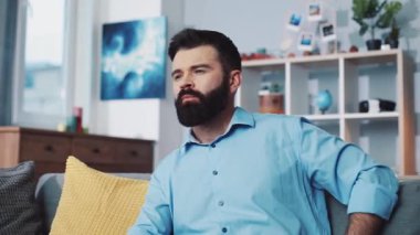 Bir adam şık bir oturma odasında televizyon seyrediyor, canlı ve eve davet edici eğlence atmosferleri sergiliyor.