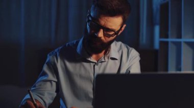 Odaklanmış bir birey, daha sonra kullanmak üzere yenilikçi fikirler ve temel notlar yakalamak için geceleri bir dizüstü bilgisayar üzerinde çalışır.