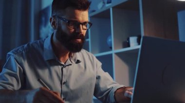 Odaklanmış bir profesyonel, loş bir çalışma alanında yüksek verimlilik seviyelerini gösteren bir dizüstü bilgisayar kullanıyor.