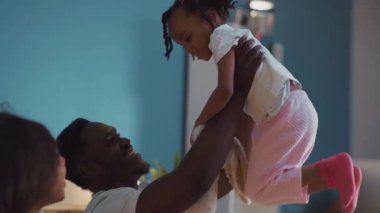 Sevimli genç adam küçük sevimli kızını kucağında tutuyor ve gülümsüyor..