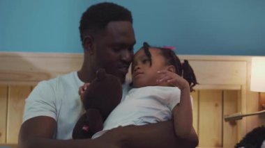 Gülümseyen Afrikalı Baba ve Kızı evde sarılıp dinleniyorlar. Sevimli bir aile fotoğrafı..