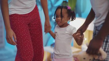 Güzel, genç bir Afrikalı aile evde birlikte dans ediyor. Örgü örüp ailesinin elini tutan küçük siyah bir kızın şirin portresi..