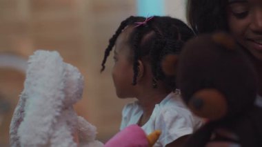 Baridleri olan, yumuşak oyuncakları olan ve evde oynayan sevimli Afrikalı çocuğun yakın çekimi..