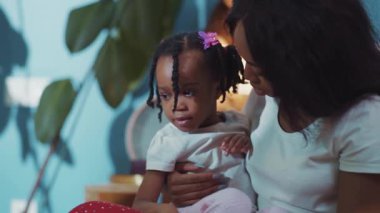 Kucağında kızını tutan Afrikalı güzel bir annenin şirin yakın plan portresi. Güzel Etiyopyalı anne ve kız içeride sarılıyorlar..