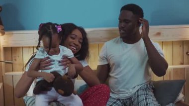 Güzel, genç Afrikalı bir anne kucağına alıp, kameraya gülümseyen küçük çocuğunu büyütüyor. Mutlu ebeveyn ve çocuğun birlikte oynadığı güzel bir portre..