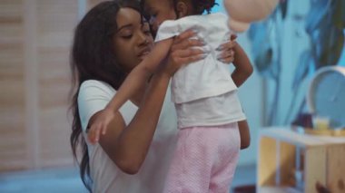 Neşeli siyah Etiyopyalı anne çocuğunu kucağında tutuyor ve güzel kızını evde yetiştiriyor..
