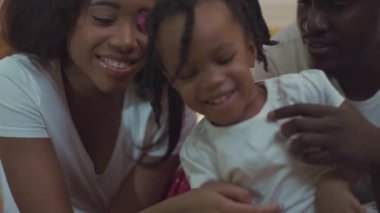 Mutlu Afro-Amerikan genç aile portresi. Güzel, küçük bir kız çocuğu ve anne babası yataktaymış..