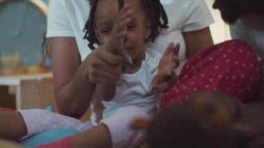 Çok tatlı bir Afro-Amerikan kızının annesinin kucağında oturup el çırpışını ve eğlenişini yakından izliyoruz..