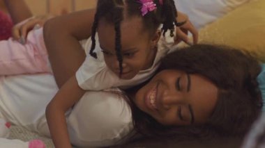 Mutlu, gülümseyen Afrikalı bir annenin genç kızıyla evde uzanması..