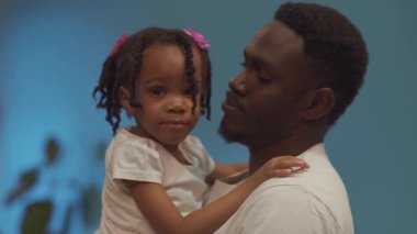 Tatlı Afro-Amerikan aile portresi. Mutlu baba kucağında ve kucağında küçük kızı.