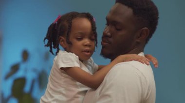 Sevimli Afrikalı baba kucağında küçük tatlı kızını kucağında tutuyor..