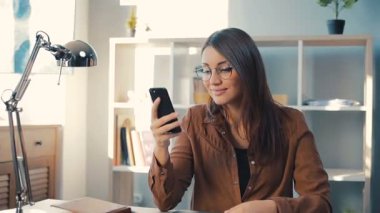 Güzel Ukraynalı kız elinde akıllı telefonla ekrana bakıyor. Cihazda iyi haberlerle mesaj okuyan bir kız. Gülümsüyor.