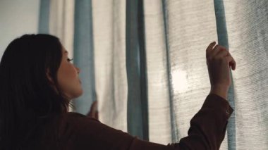 Pencereye yaklaşan, perdeleri açan güzel beyaz bir kadın. Uzağa bakan güzel, gülen kız. Kapalı.