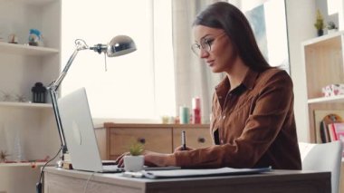 Kahverengi saçlı, zeki, beyaz bir öğrenci masada oturuyor ve ders çalışıyor. Güzel kız bakınıyor, dizüstü bilgisayar kullanıyor ve notlar alıyor. Kapalı.