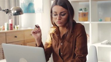 Odada dizüstü bilgisayarın başında oturan üzgün bir kız. Genç sıkıntılı beyaz kadın yanlış bilgisayar şifresini giriyor. Kapalı.