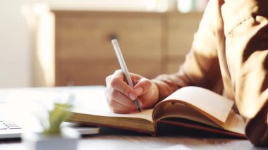 Genç bir kadın dairede masada oturuyor. Elinde kalem tutan ve günlüğe not alan bir kız. Güneşli bir gün.