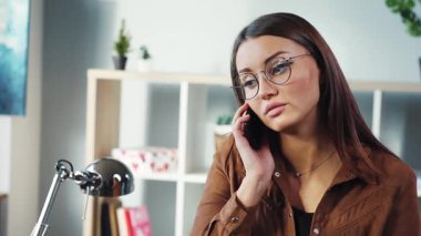 Genç ve güzel bir kız cep telefonuyla iletişim kuruyor. Koyu saçlı genç bir kadın cep telefonuna cevap veriyor, iş görüşmelerini yürütüyor. İçeride. Güneşli bir gün.