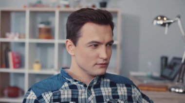 Kareli gömlek giymiş genç bir adam modern bir ofis ortamında çalışırken konsantre ve odaklanmış görünüyor.