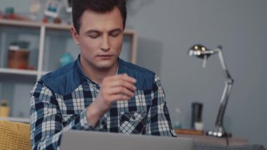 Genç bir adam, üretkenlik ve modern çalışma eğilimlerini gösteren rahat bir ofiste dizüstü bilgisayarına odaklanıyor..