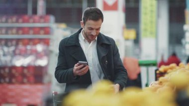 Markette elinde alışveriş arabasıyla gezen çekici genç bir adam. Müşterilerin alışveriş listelerine bakıyor. Dükkandaki yemek dükkanını seçiyor.