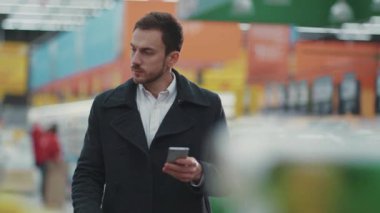Alışveriş arabalı genç bir adam. Markette yürürken telefon rehberine bakıyor. Meyve alıcısını seçiyor.