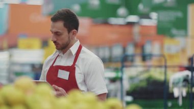 Portre satıcısı süpermarkette tablet bilgisayar kullanıyor. Kamera, gülümse. Sebze, sebze...